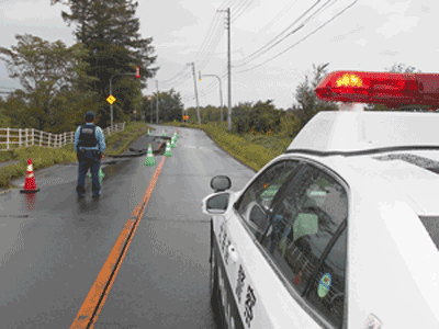 雨の中警戒活動を行う警察官の写真